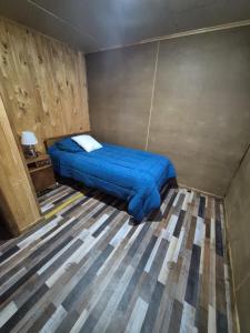 a bedroom with a bed with a blue blanket at Cabaña Gazul in Porvenir