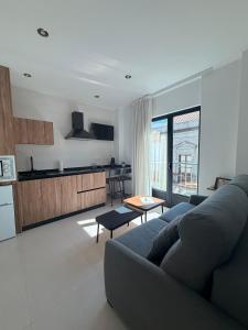 a living room with a blue couch and a kitchen at Quercus in Pozoblanco