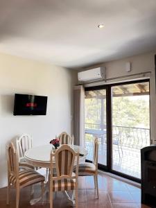 a dining room with a table and chairs and a tv at green & blue villa in Glykadi