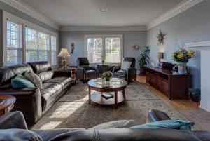 Nantucket Inn - Anacortes في أناكورتس: غرفة معيشة مع أريكة جلدية وكراسي