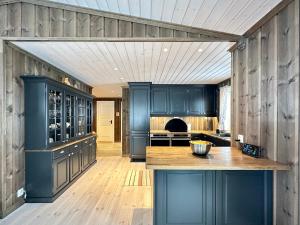 a kitchen with navy blue cabinets and a wooden floor at High-standard cabin with jacuzzi & stunning views in Øyer