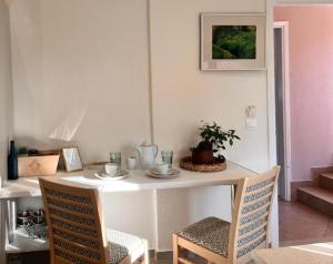 a dining room table with two chairs and a table with a plant at green & blue villa in Glykadi