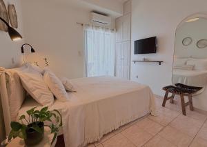 a white bedroom with a bed and a mirror at Selini Apartments Mani in Agios Nikolaos
