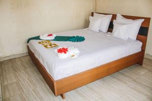 a bed with white sheets and flowers on it at Hotel National Ambanja in Ambanja +1 photo