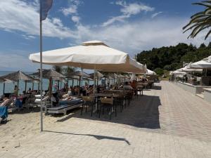 people sitting at tables under an umbrella on the beach at Siviri Serenity, 3 minutes walk from the Beach in Siviri