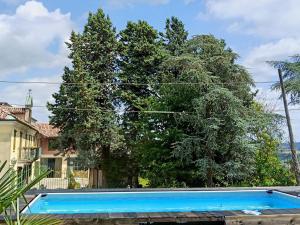 a blue swimming pool in front of a tree at La vigna in Costigliole dʼAsti +2 photos