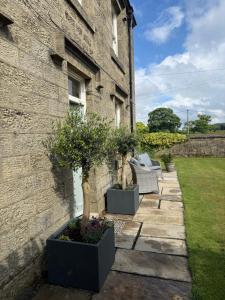 a patio with two chairs and trees in front of a building at Bewerley Hall farm in Harrogate