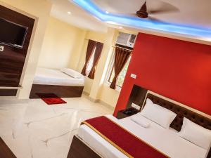 a bedroom with two beds and a red wall at Vaidehi Inn-A Unit of vaidehi guest house in Deoghar