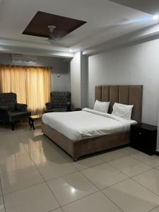 a bedroom with a large bed and two chairs at We Hotels in Islamabad