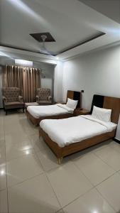 a hotel room with three beds and a couch and chairs at We Hotels in Islamabad