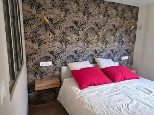 a bedroom with a bed with two red pillows at La Part'Thé in Crouy-sur-Cosson