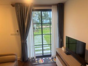 a living room with a television and a large window at สวนไผ่รีสอร์ท in Ban Na