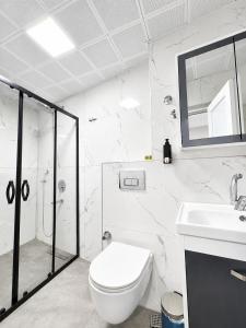 a white bathroom with a toilet and a sink at Kaya Hotel in Antalya +17 photos