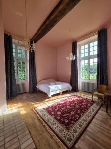 a bedroom with a bed and a rug and windows at Château de Beaumanoir in Évran