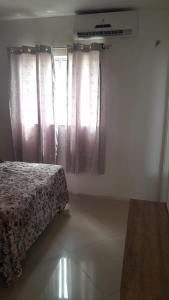 a bedroom with a bed and a window with curtains at AP da Vicky 2 quartos central São Luis in São Luís