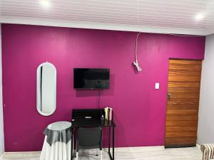a pink wall in a room with a desk and a tv at Human on Ten BnB in Summer Pride