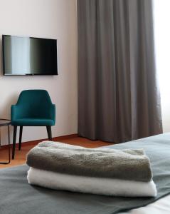 a bedroom with a bed with a chair and a flat screen tv at Hotel Sächsischer Hof in Pirna