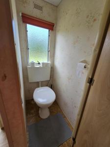a small bathroom with a toilet and a window at Domki u Agi in Głęboczek +8 photos