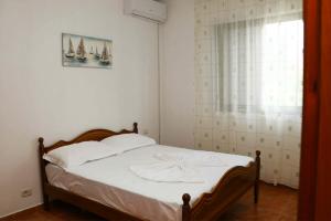 a bedroom with a bed with white sheets and a window at La Famiglia Villa in Velipojë