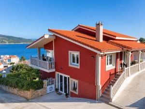 a red house with the ocean in the background at Hospedium Galitrips Vila Maruja Corme in Corme-Puerto