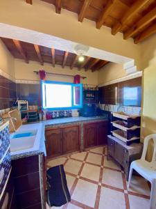 a kitchen with wooden cabinets and a large window at Grotte pied dans l'eau in Aglou
