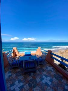 a patio with a table and chairs on the beach at Grotte pied dans l'eau in Aglou