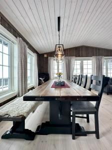 a dining room with a large wooden table and chairs at High-standard cabin with jacuzzi & stunning views in Øyer