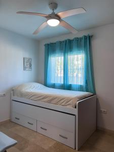 a bedroom with a bed with a ceiling fan at Chalet Adosado en Playa La Barrosa in Novo Sancti Petri