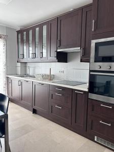 a kitchen with wooden cabinets and a sink and a microwave at Chalet Adosado en Playa La Barrosa in Novo Sancti Petri