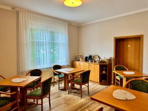 a dining room with tables and chairs and a kitchen at Pension Sellent in Stendal