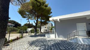 a white building with a tree and a fence at Vlora forest Apartments in Vlorë