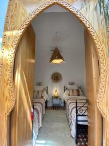 two beds in a room with an arched doorway at Dar Dada Riad climatisé à votre disposition dans sa totalité et de façon exclusive in Safi
