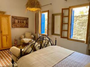 a bedroom with a bed and a chair and windows at Dar Dada Riad climatisé à votre disposition dans sa totalité et de façon exclusive in Safi