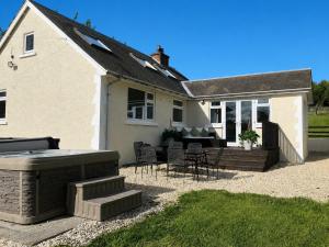 a house with a patio with a grill and chairs at Satchells Cottage in Melrose