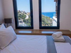 a bedroom with a bed with two large windows at Blue Dawn Kalymnos in Kalymnos