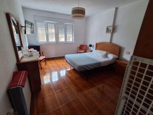 a bedroom with a bed and a wooden floor at Las 4 columnas (MFA) in Muxia