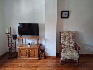 a living room with a chair and a tv and a guitar at Las 4 columnas (MFA) in Muxia