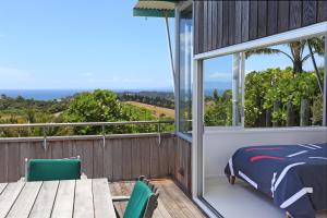a bedroom with a bed and a table on a balcony at The Nikau Loft in Onetangi