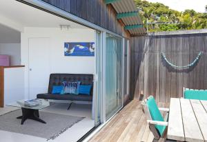 a patio with a bench and a table and chairs at The Nikau Loft in Onetangi
