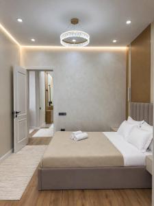 a bedroom with a large bed and a chandelier at Современные 2-комнатные апартаменты в ЖК Capital City рядом с Shym City Park in Shymkent
