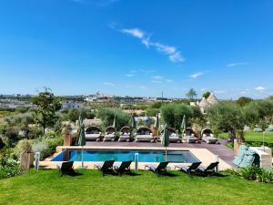a swimming pool with lounge chairs and a lawn at Trulli Damari in Locorotondo