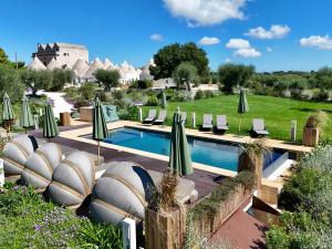 a pool with chaise lounge chairs and umbrellas at Trulli Damari in Locorotondo +72 photos