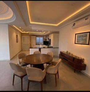 a dining room with a table and chairs and a kitchen at Villa Wissal Djerba piscine privée in Arkou