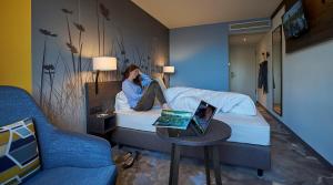 a man sitting on a bed with a laptop on a table at Hwest Hotel in Hall in Tirol