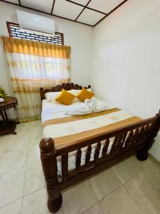 a bedroom with a wooden bed with yellow pillows at The Travellers Rest in Katunayaka