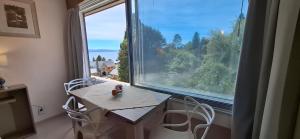 a table and chairs in a room with a large window at El encanto del lago in San Carlos de Bariloche