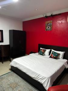 ein Schlafzimmer mit einem großen Bett und einer roten Wand in der Unterkunft Solitaire hotel in Lagos + 11 Fotos