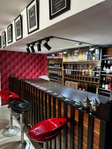 Eine Bar mit roten Barhockern in einem Raum mit Weinflaschen in der Unterkunft Solitaire hotel in Lagos