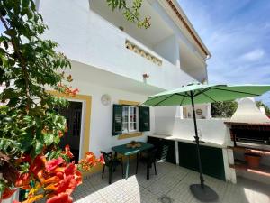 a patio with a table and a green umbrella at Milfontes Villa in Vila Nova de Milfontes