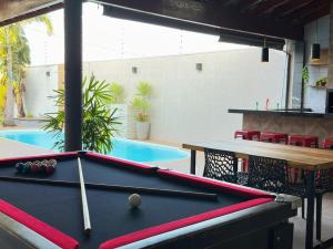 a pool table in front of a swimming pool at Refúgio com Fogueira, Piscina, Bilhar e Ar condicionado in Nova Odessa